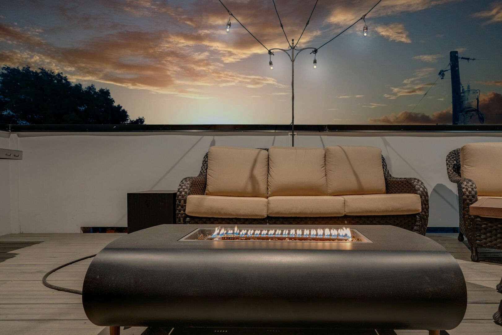 Unit 2: Rooftop balcony with outdoor BBQ, smart TV, fire pit, lounge area, and bistro lights.