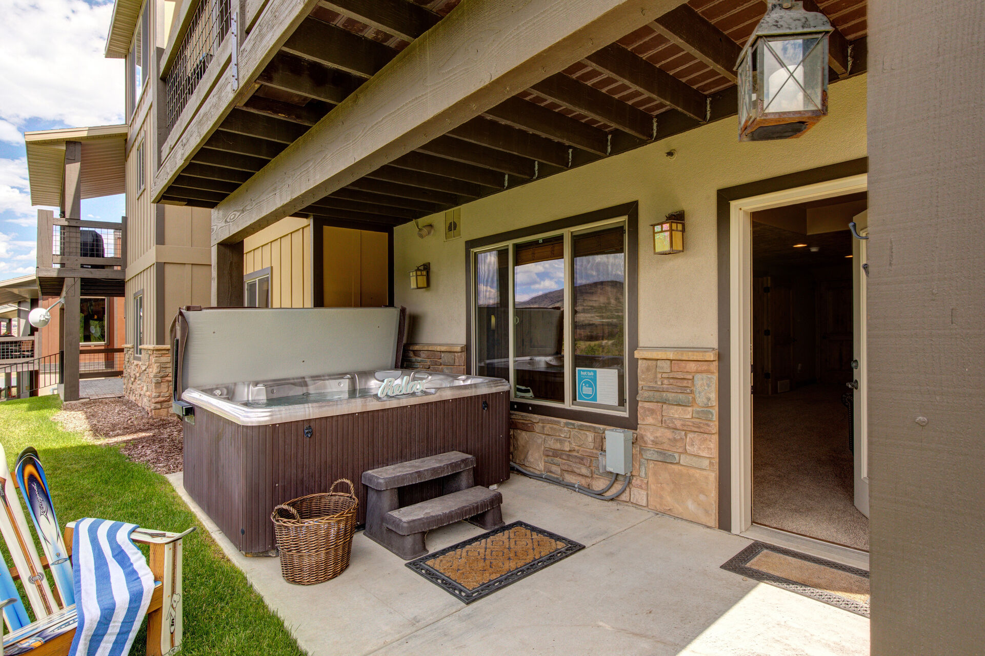 Lower Level Private Hot Tub Patio and back yard with Adirondack chairs, corn hole game, 8-person hot tub, and stunning surrounding views