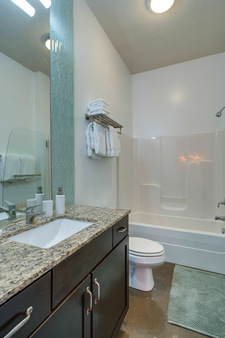 Spacious bathroom with large mirror and shower/tub combo.