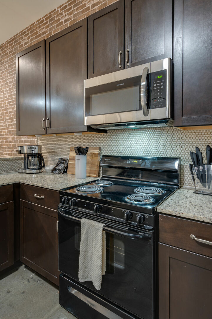 Fully stocked kitchen with basic cooking essentials, stainless steel appliances, granite counter tops and breakfast bar seating.
