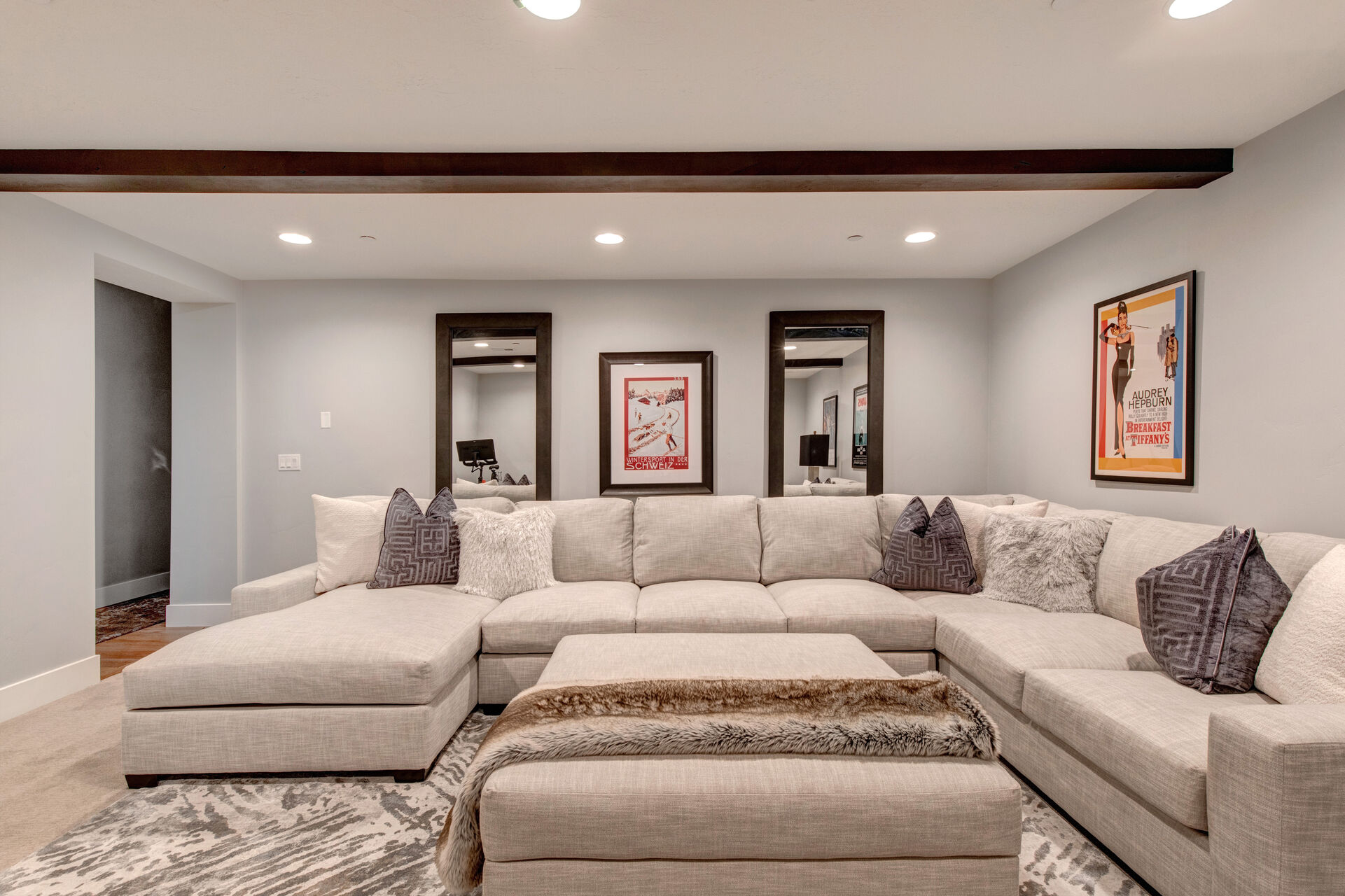 Lower Level Theatre Room with over-sized sectional, Peloton bike, work desk, and 65