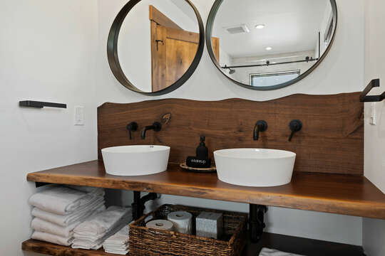 Downstairs en-suite bath includes custom live edge wood vanity and 2 sinks.