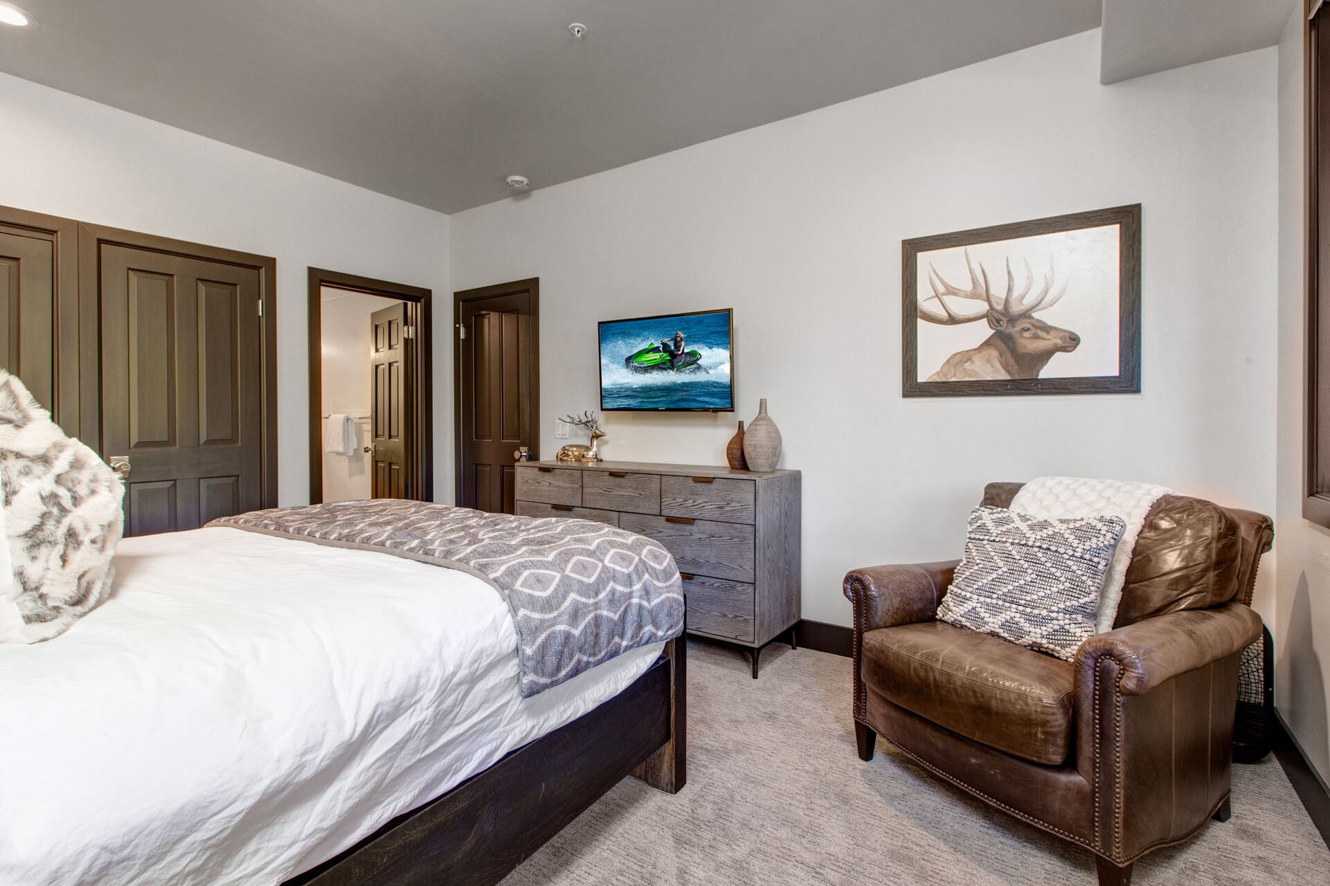 Bedroom 2 with queen bed, plush arm chair, Smart TV, and en suite bathroom