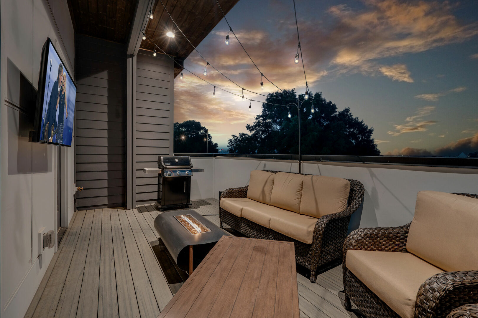 3rd unit: Rooftop balcony with fire pit, smart TV, outdoor BBQ, and lounge area. All draped in bistro lights.
