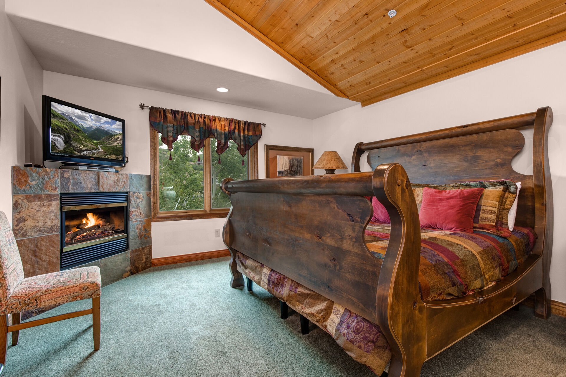 Master Bedroom with king bed, TV, gas fireplace, vaulted ceiling, and en suite bathroom