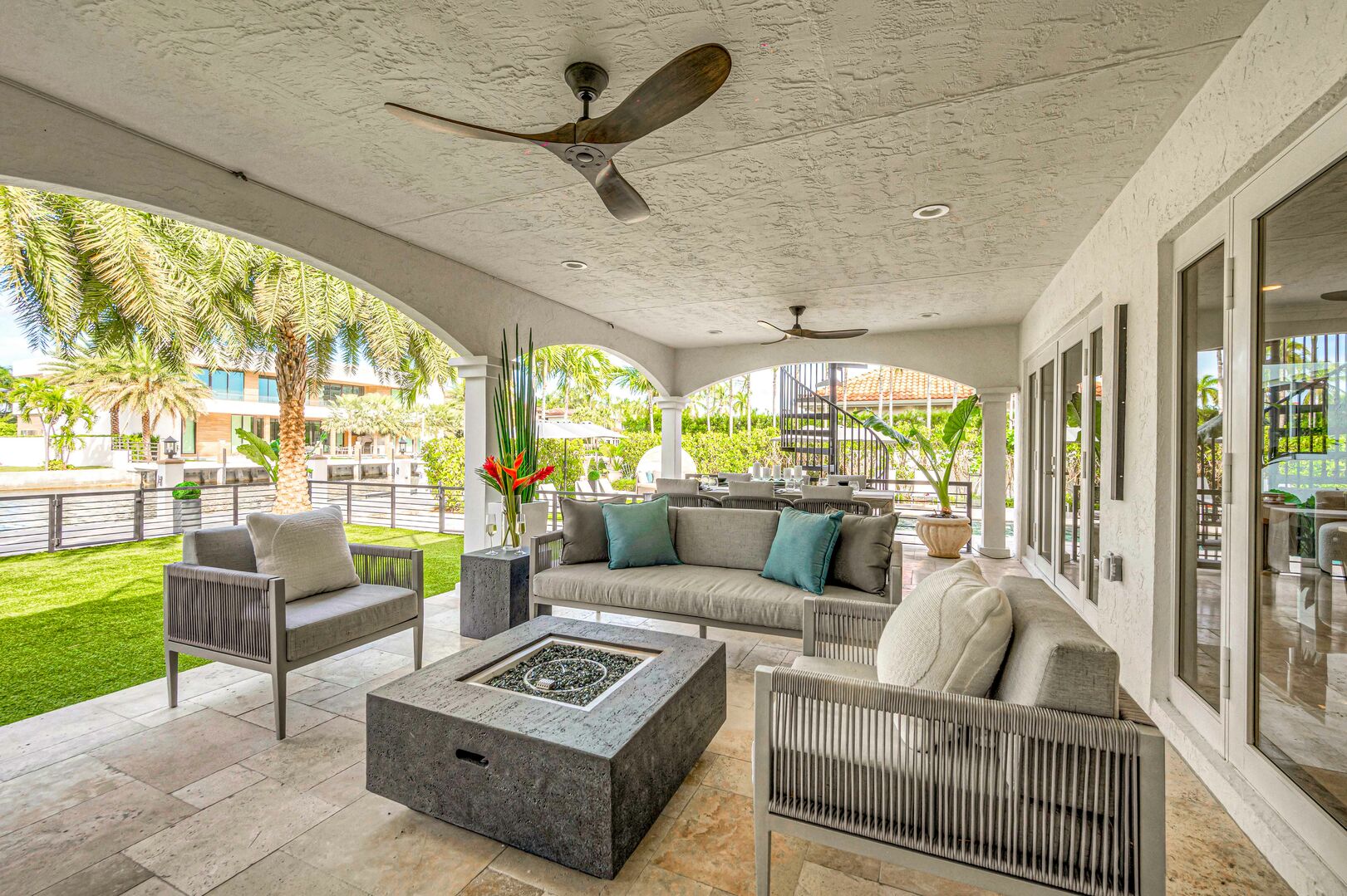 The covered patio contains a dining table for eight and a sitting area with TV and fire pit.