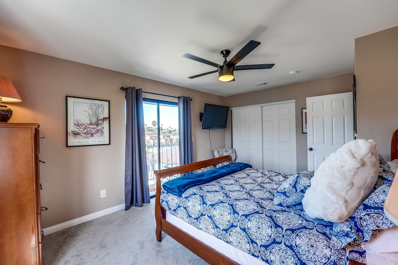 Master bedroom has a remote-controlled ceiling fan, ample storage in dresser and closet, smart TV, and small balcony with refreshing coastal breeze!