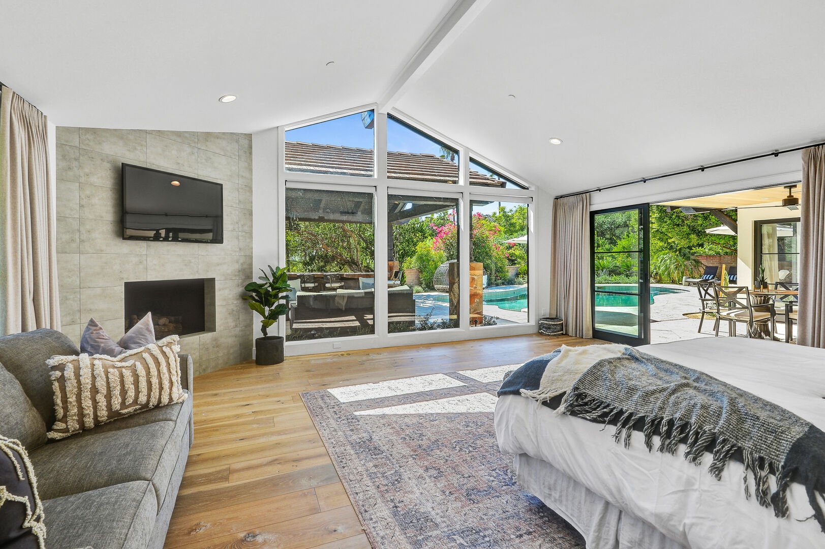 The master bedroom offers a view through picturesque windows towards the pool and gazebo.