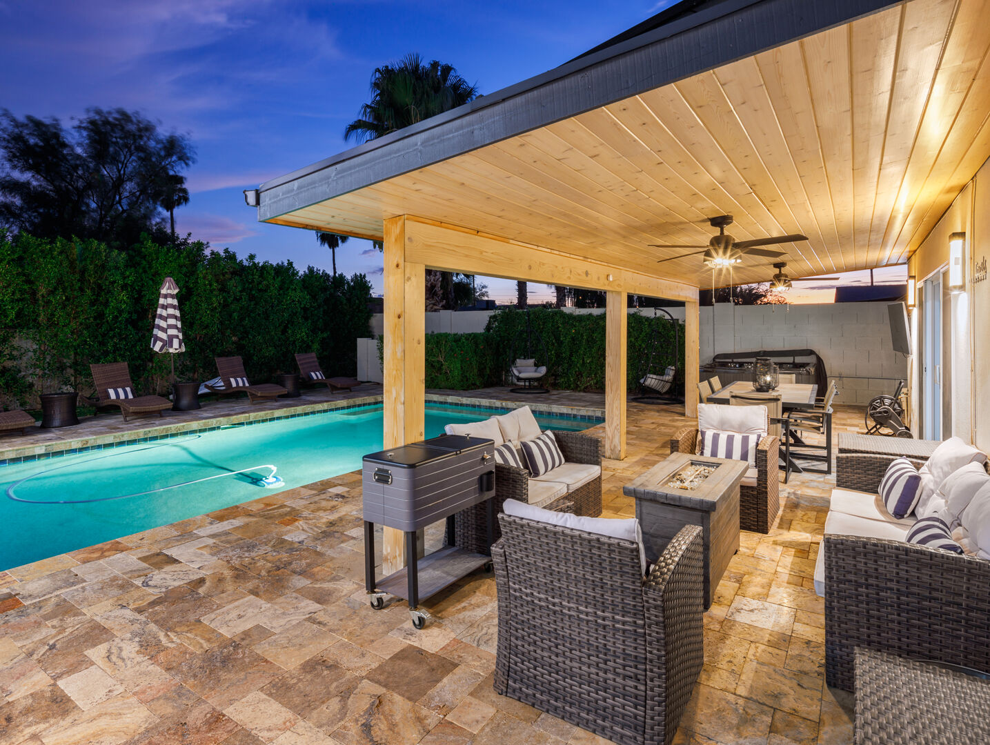 Large covered patio with fire pit, BBQ grill, and outdoor dining table. Overlooks pool area.