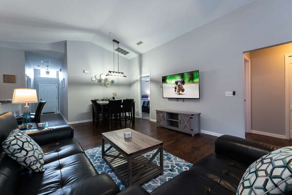 Open floor plan showing sofa and loveseat with wall-mounted Smart TV