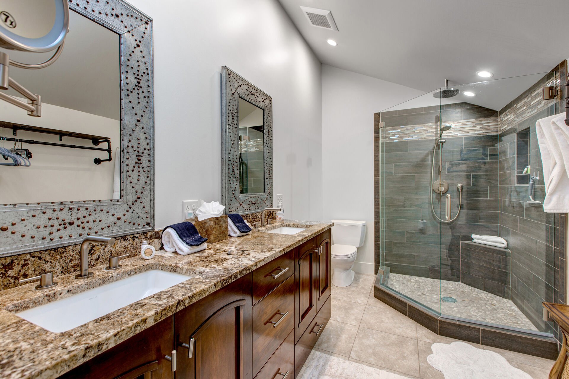 Shared Full Bathroom with double sinks, and tile and glass shower
