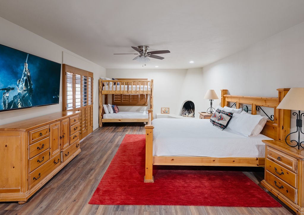 Primary bedroom with King bed, twin bunk beds, fireplace, smart tv, backyard access, and en-suite bathroom