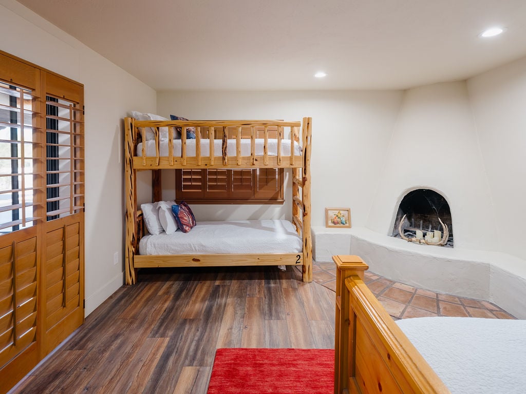 Primary bedroom with King bed, twin bunk beds, fireplace, smart tv, backyard access, and en-suite bathroom