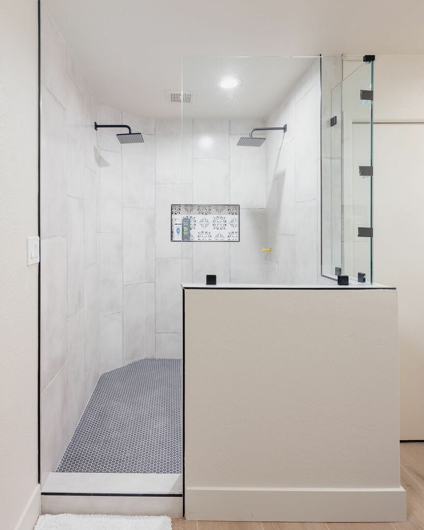 Primary bathroom with large walking in standing shower, dual vanity sink, and bathtub.