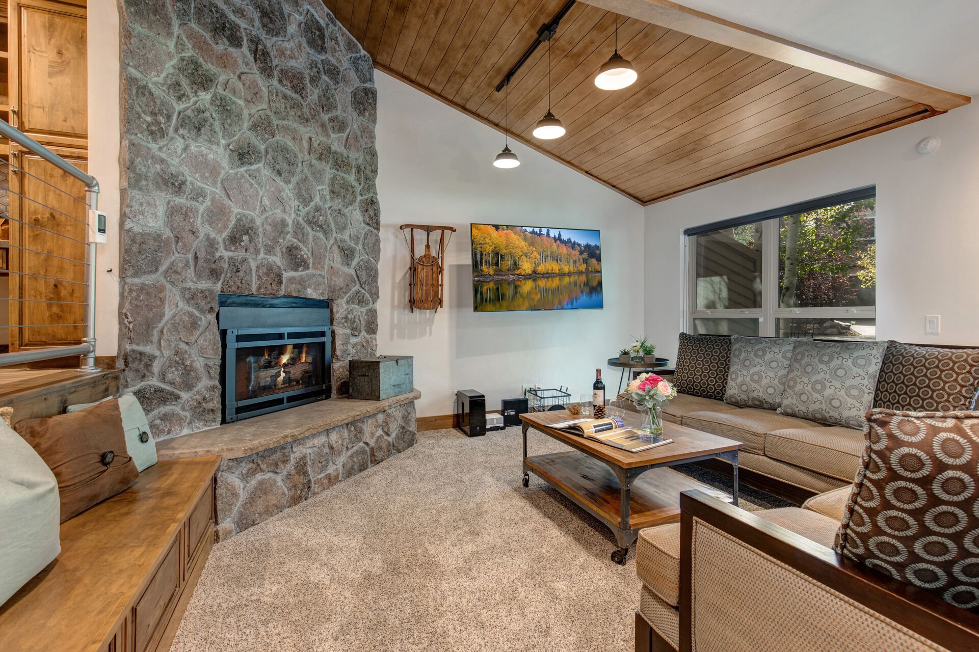 Living Room with cozy gas fireplace, Smart TV, plush furnishings, vaulted ceiling, and patio access.