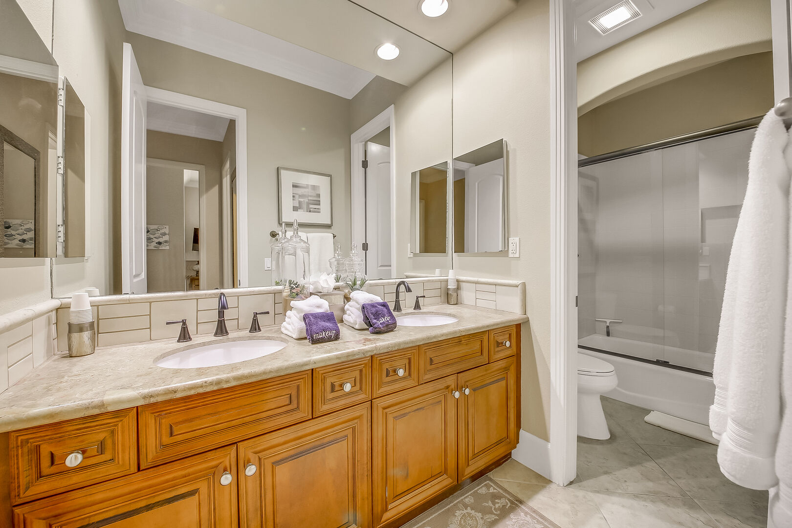 The hallway bathroom is next to the laundry room and features features a shower bathtub combo and double vanity sinks.