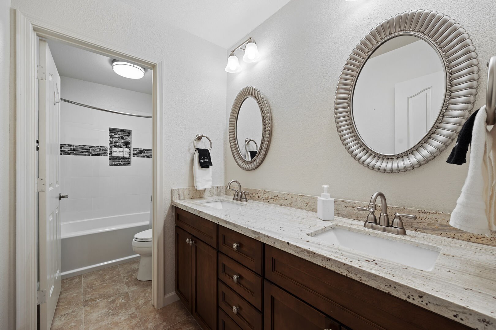 Shared bathroom with double vanity sinks and a shower/tub combo.
