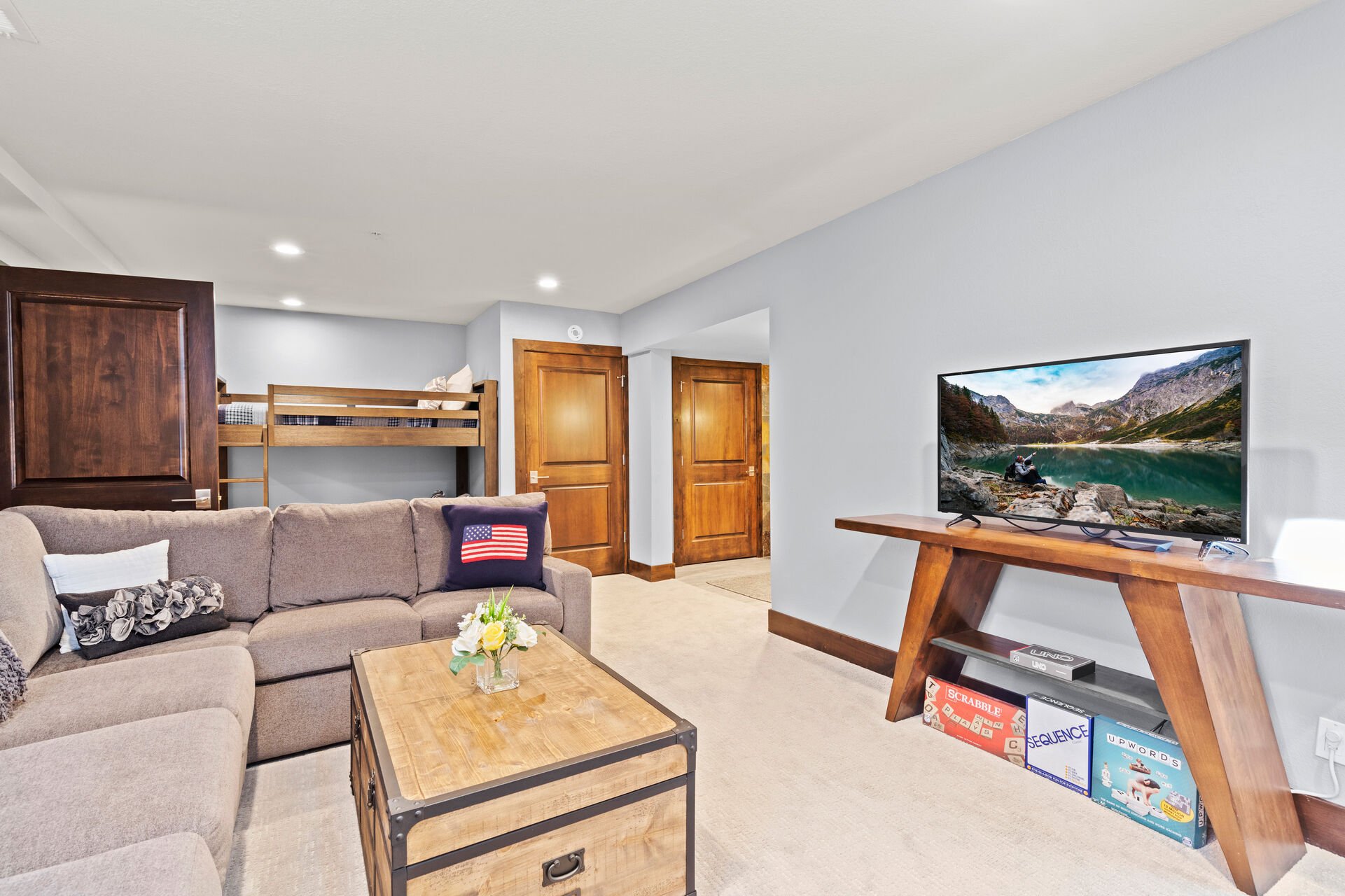 Lower Level Living Room with plush sectional, wet bar & wine fridge, twin over twin bunkbeds, and full bath access