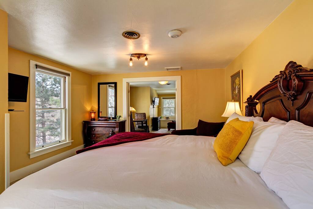 The Manitou Suite - A luxury two-room king suite featuring a dark burl wood king bed, with luxurious pillow top mattress, and hotel quality linens. French doors divide the 2 large rooms with TV at the foot of the bed.