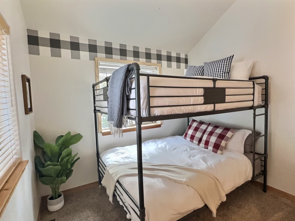 Guest Sanctuary: Nestle into cozy comforters atop pillow-top mattresses in a quaint guest bedroom, featuring luxurious Queen over Queen bunk beds. 
