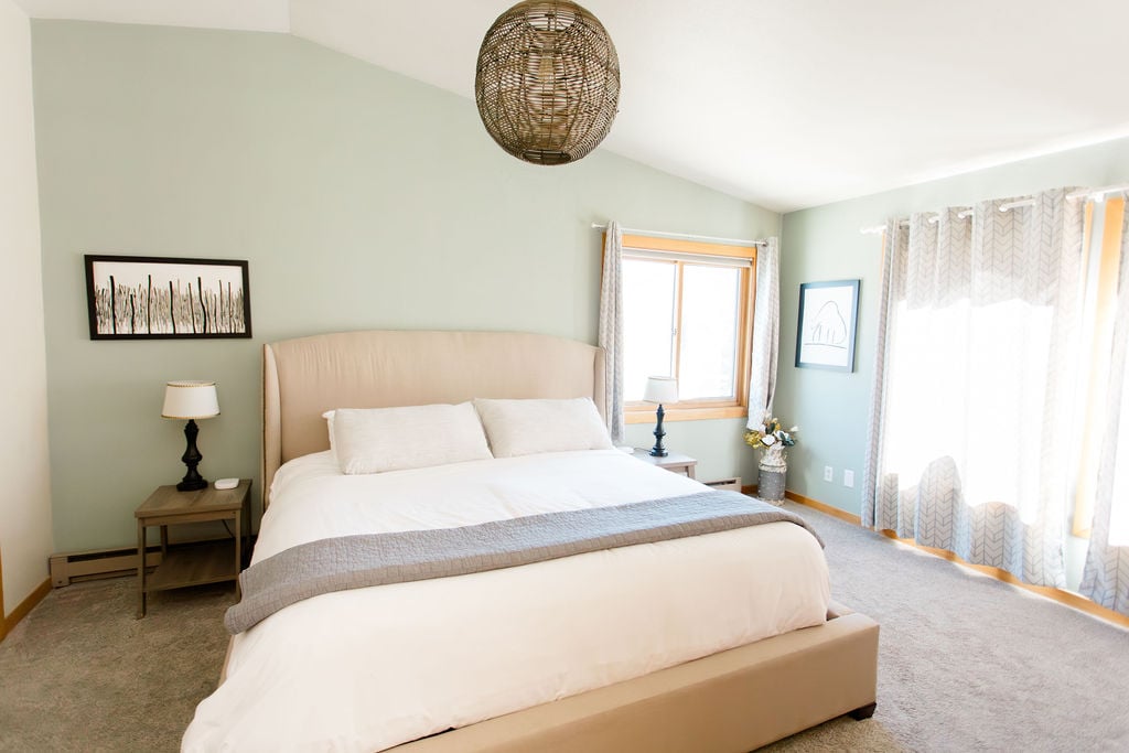 The upstairs master bedroom boasts a king-sized bed with plush bedding, an ensuite bathroom, and epic views of the surrounding mountains. It's a luxurious escape offering tranquility and comfort.