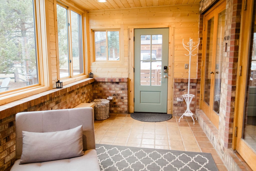 Enter The Summit House into a large, multifunctional sunroom, offering ample space for ski gear, boots, and luggage, plus a cozy sitting area for relaxation and enjoying the view of the yard. 