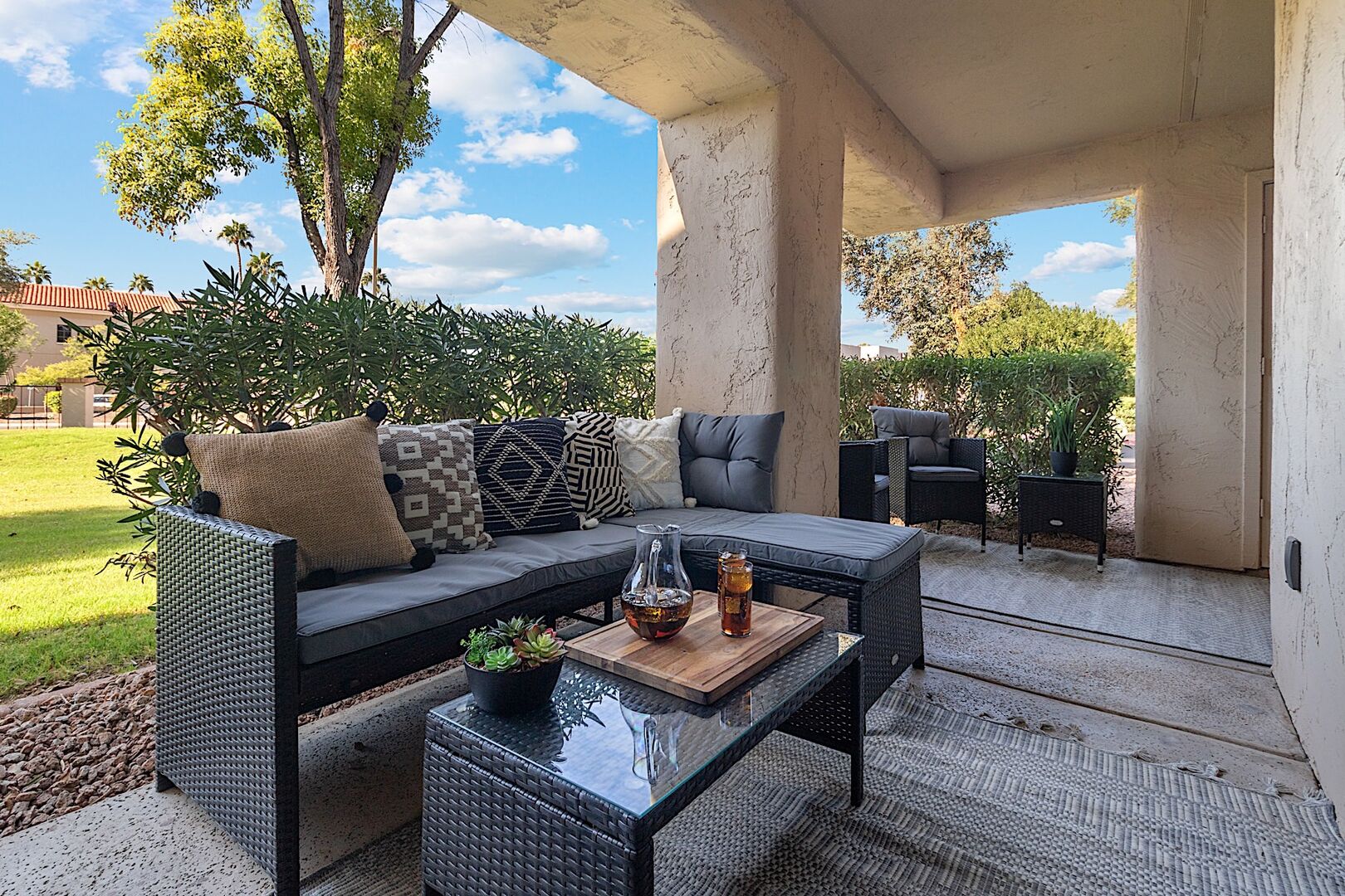 Private patio w/ L-shaped outdoor sofa, coffee table and two sitting chairs.