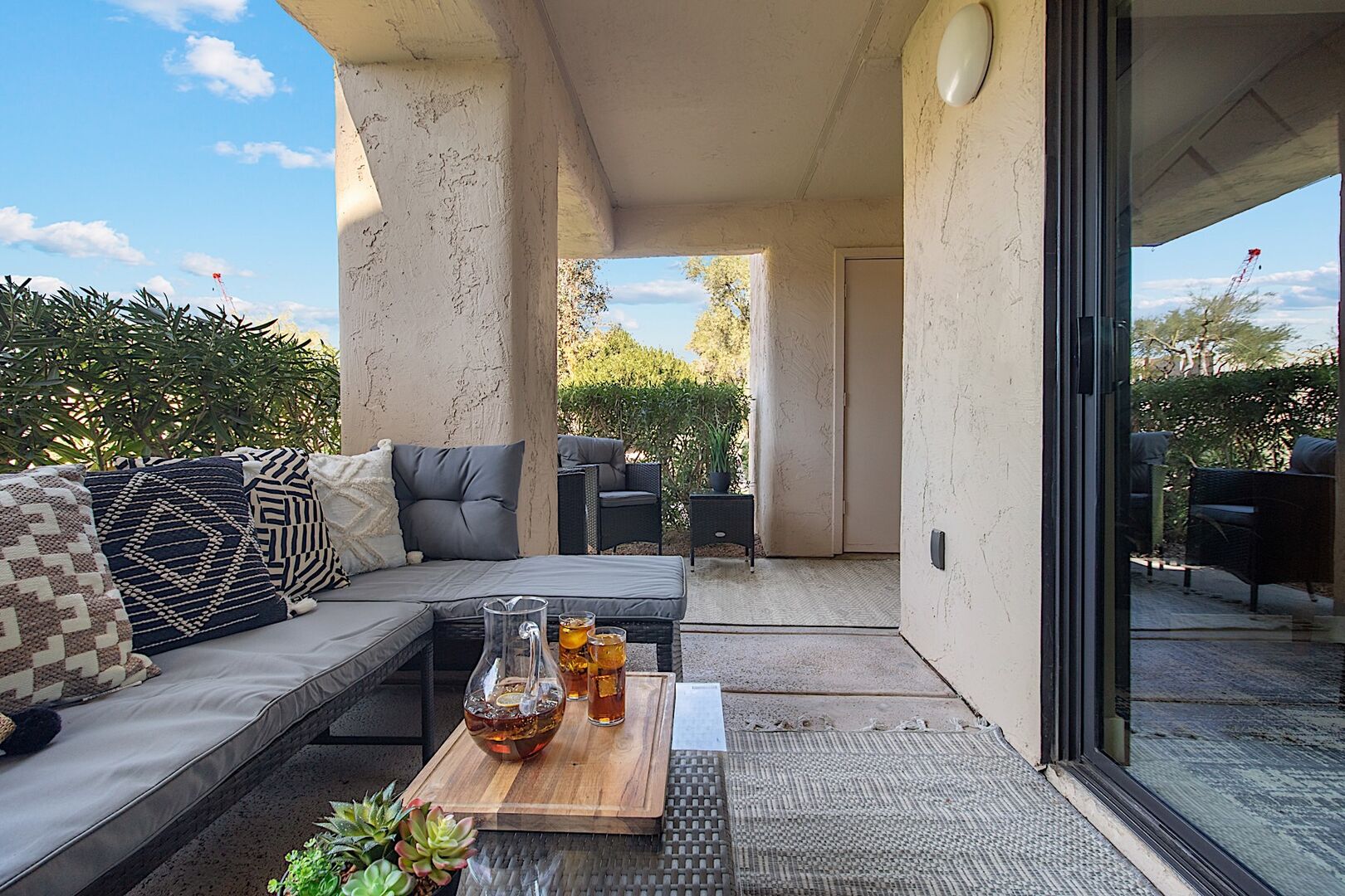 Private patio w/ L-shaped outdoor sofa, coffee table and two sitting chairs.