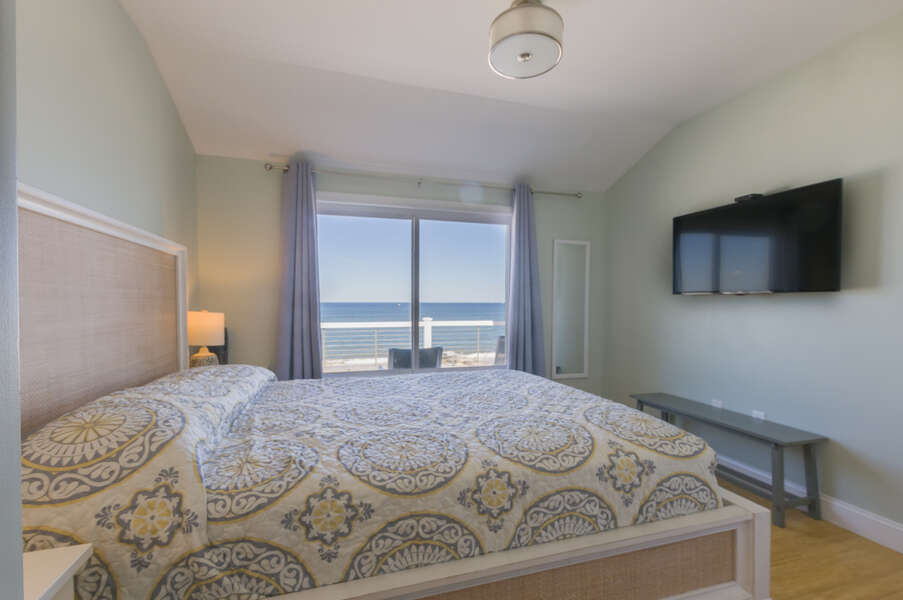 Primary bedroom with a queen bed, flat screen tv and stunning ocean views.