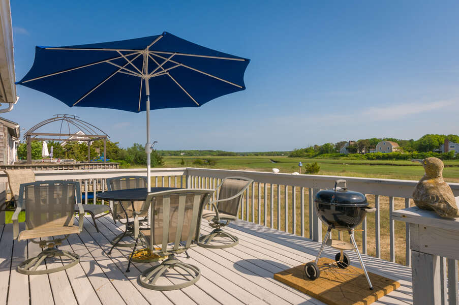 Back deck with seating for the family, umbrella and charcoal grill.
