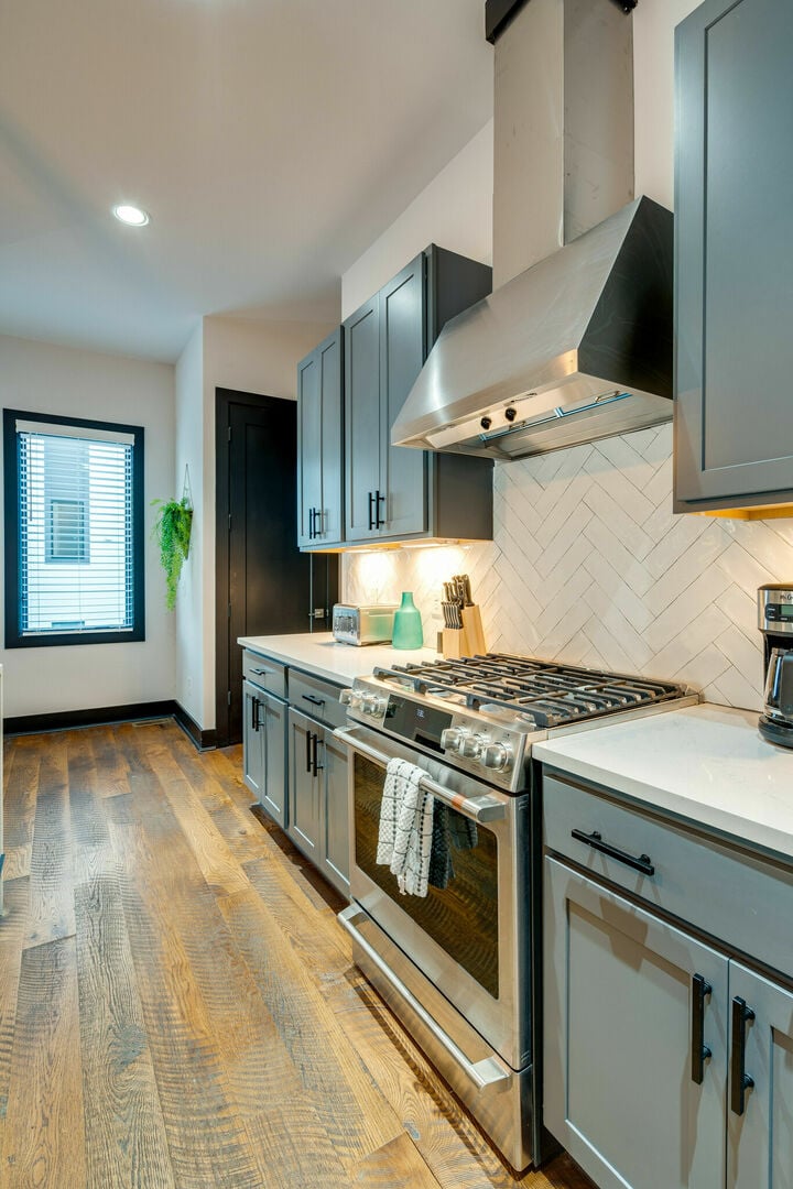 2nd Unit: Fully equipped kitchen with stainless steel appliances, breakfast bar seating, and bar stools.