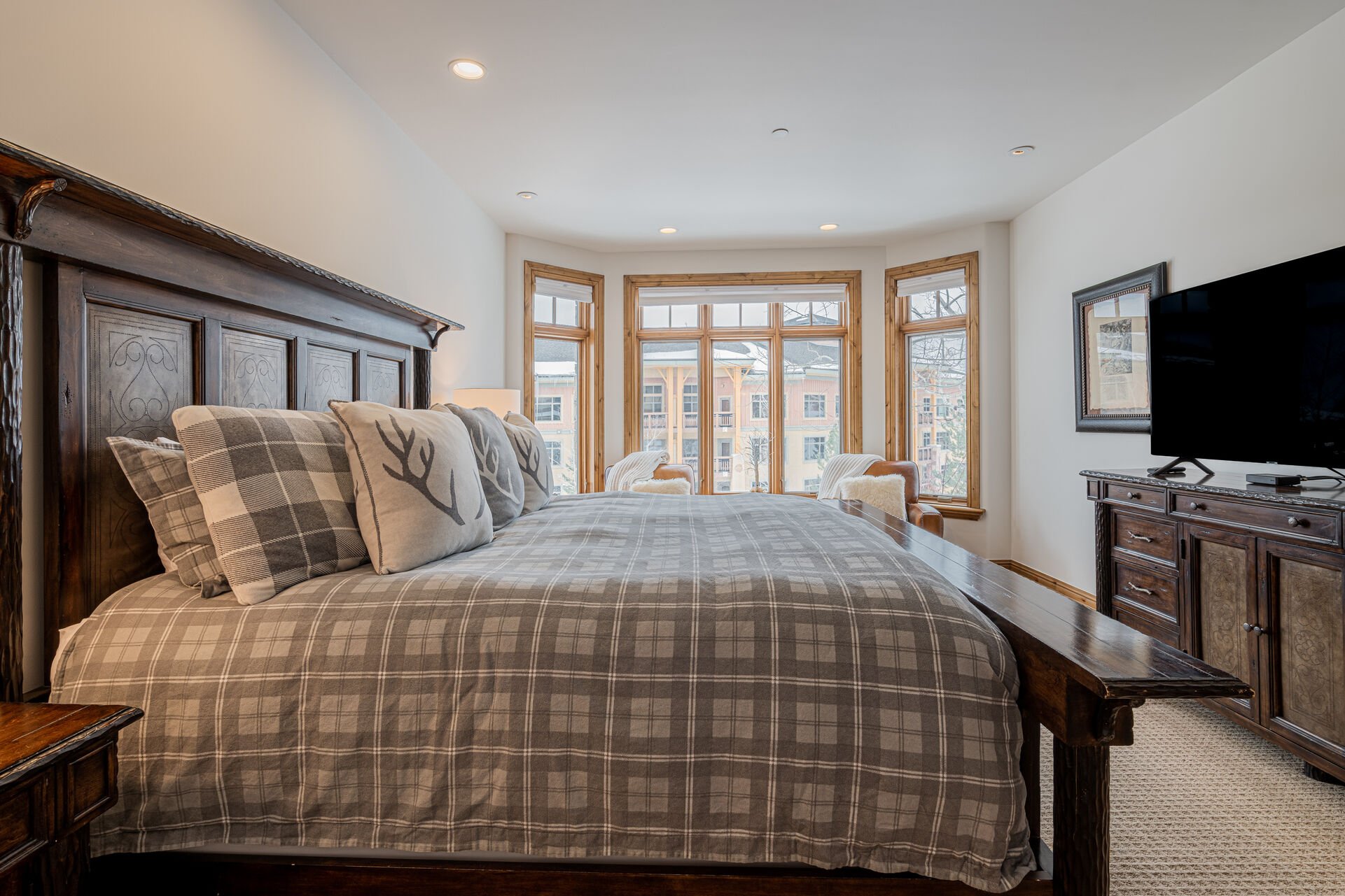 Master bedroom with King bed, two leather armchairs, 55” Smart TV, and a private bath