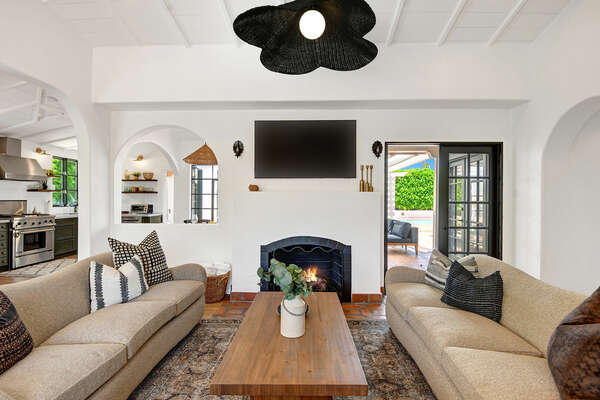 THE SPANISH STYLE OVERSIZED LIVING ROOM SITS IN THE MIDDLE OF THE PROPERTY WITH FLATSCREEN TV AND FIREPLACE