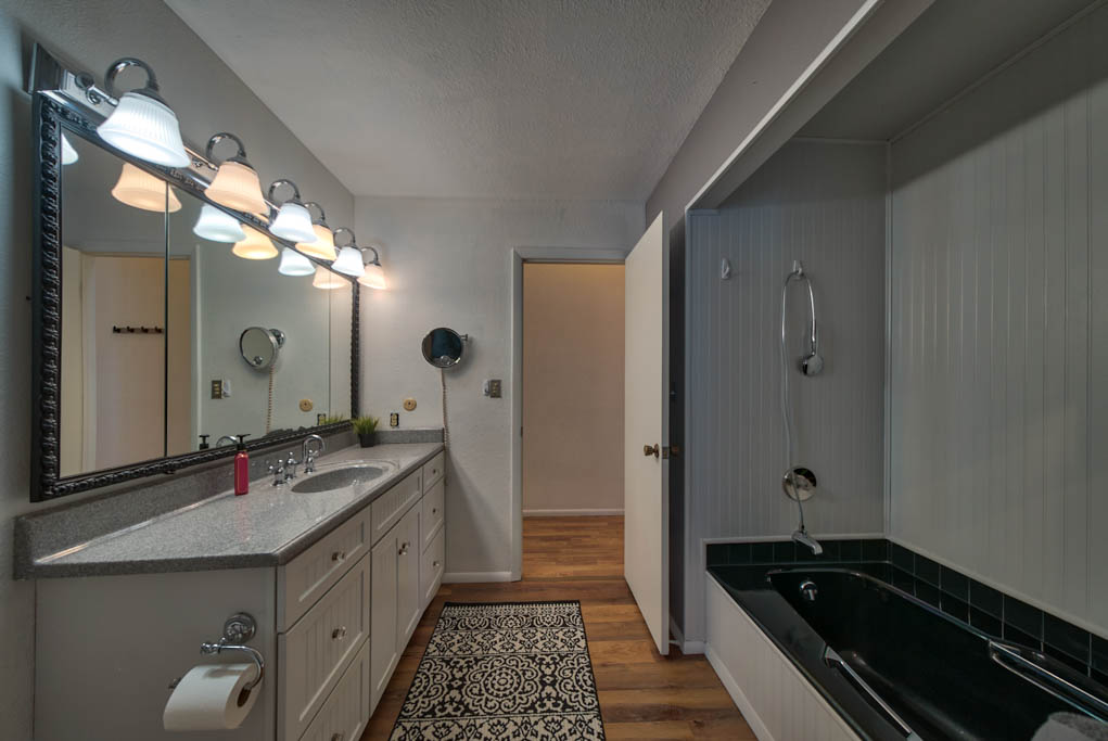 Bathroom off of hallway with bathtub and large vanity