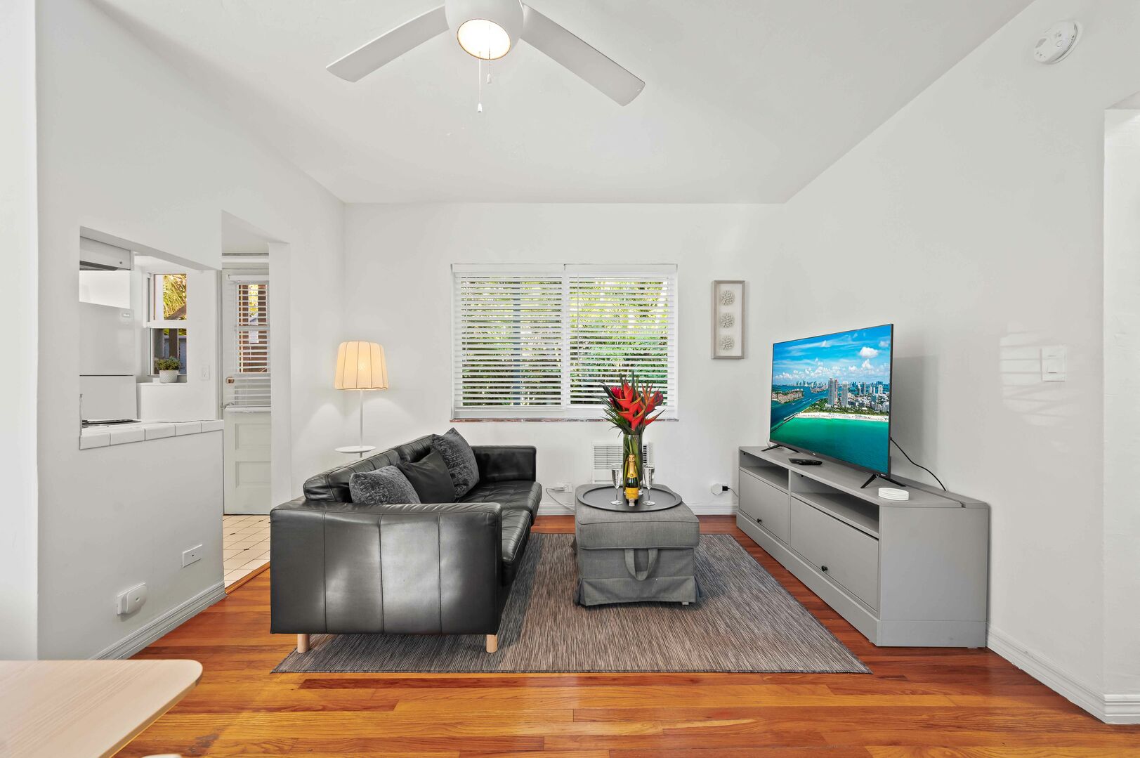 The bright living room has plenty of natural light, a sofa and a Smart TV.