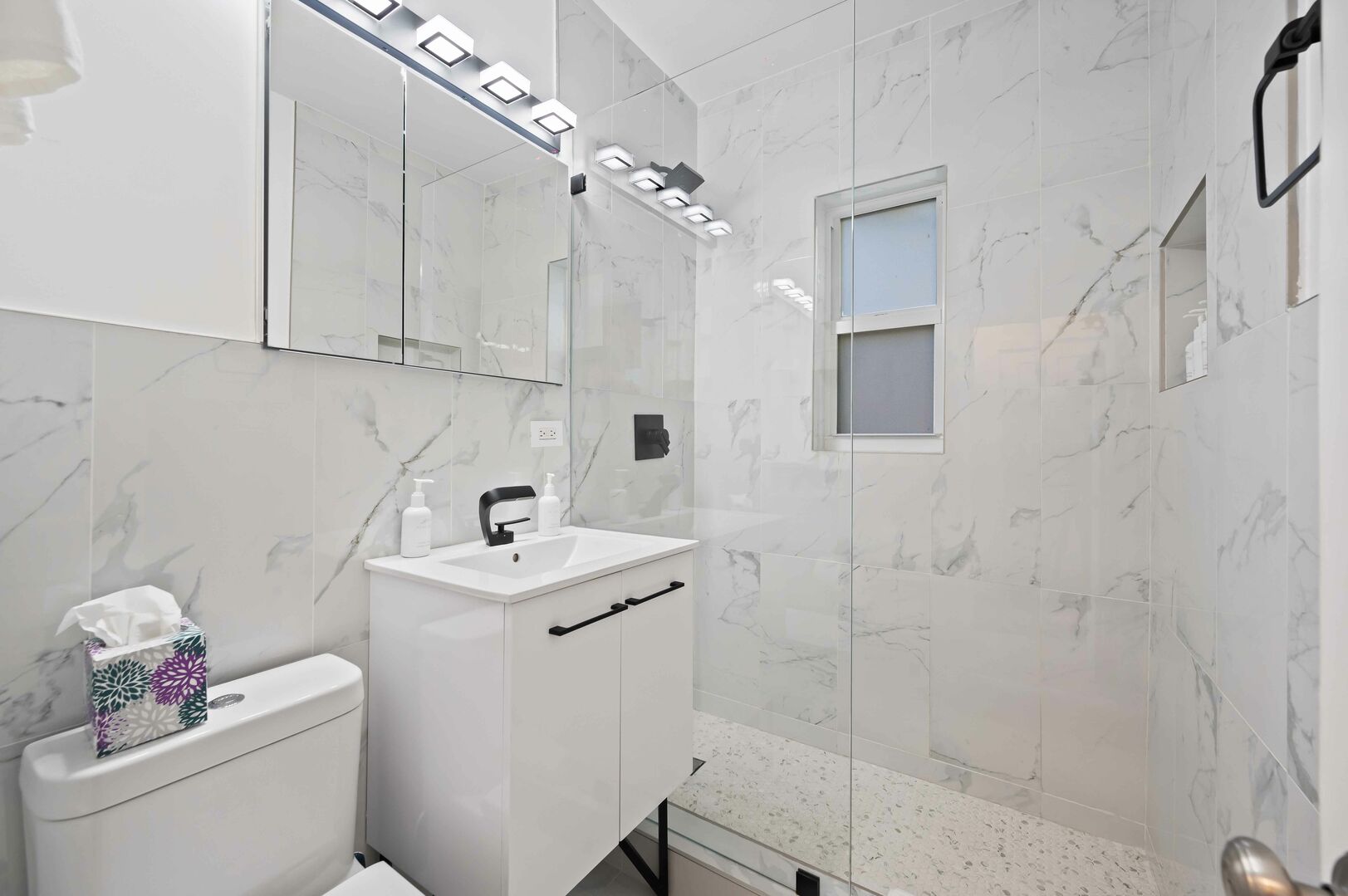 The black and white marbled bathroom features a walk-in shower.
