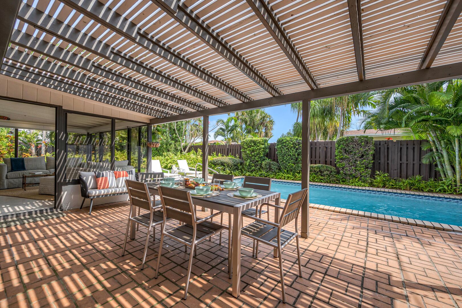 Shaded poolside al fresco dining with a grilling area in the lush garden.