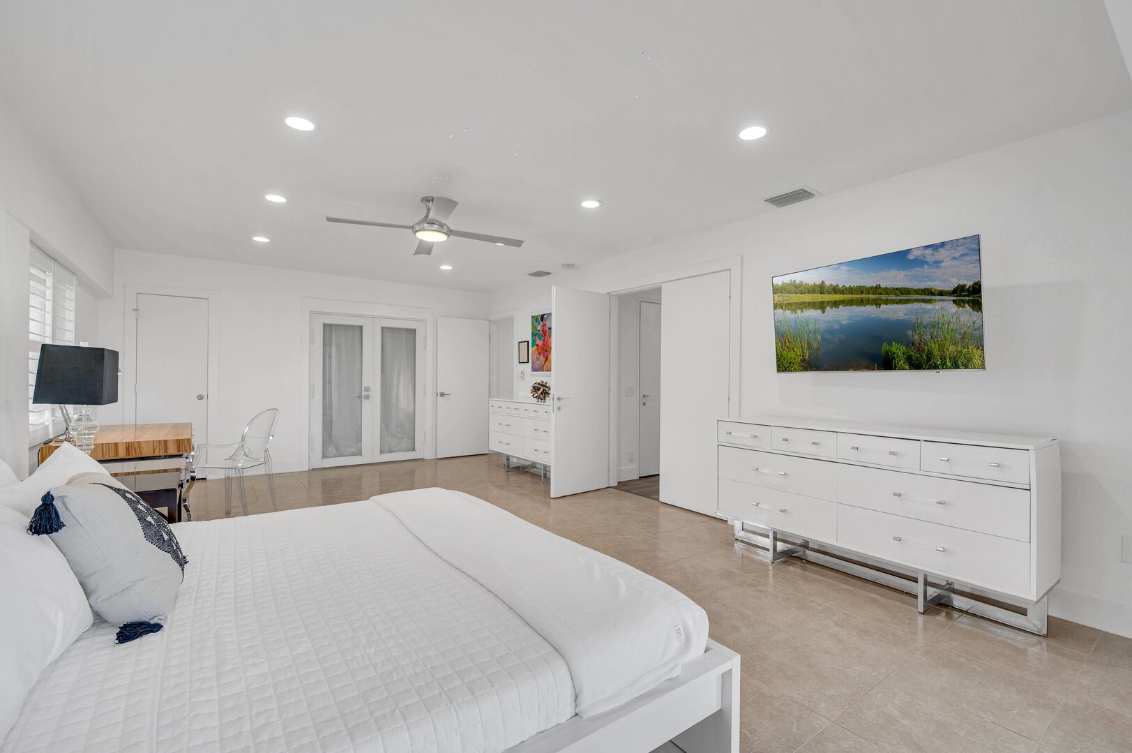 The primary bedroom boasting waterfront views features a king size bed, Smart TV, and a desk.