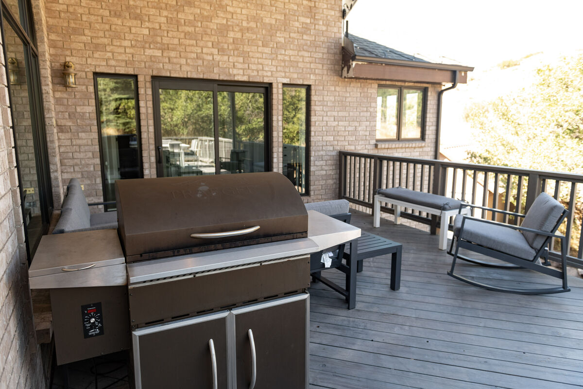 Just outside the kitchen is the rear upper deck with seating for 10 and a Traeger BBQ.  Also on the deck is a large outdoor dining table.  The deck looks out onto the North Heber Valley hillside just above Coyote Ridge.
