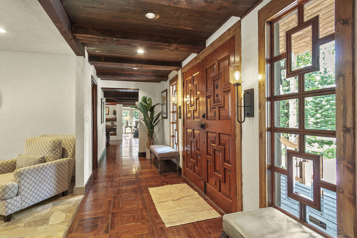Grand custom wooden doors are the main entryway to the home. Flowing into the coffee lounge area and kitchen straight ahead. Or walk to the east or west wing of the home from this entryway.
