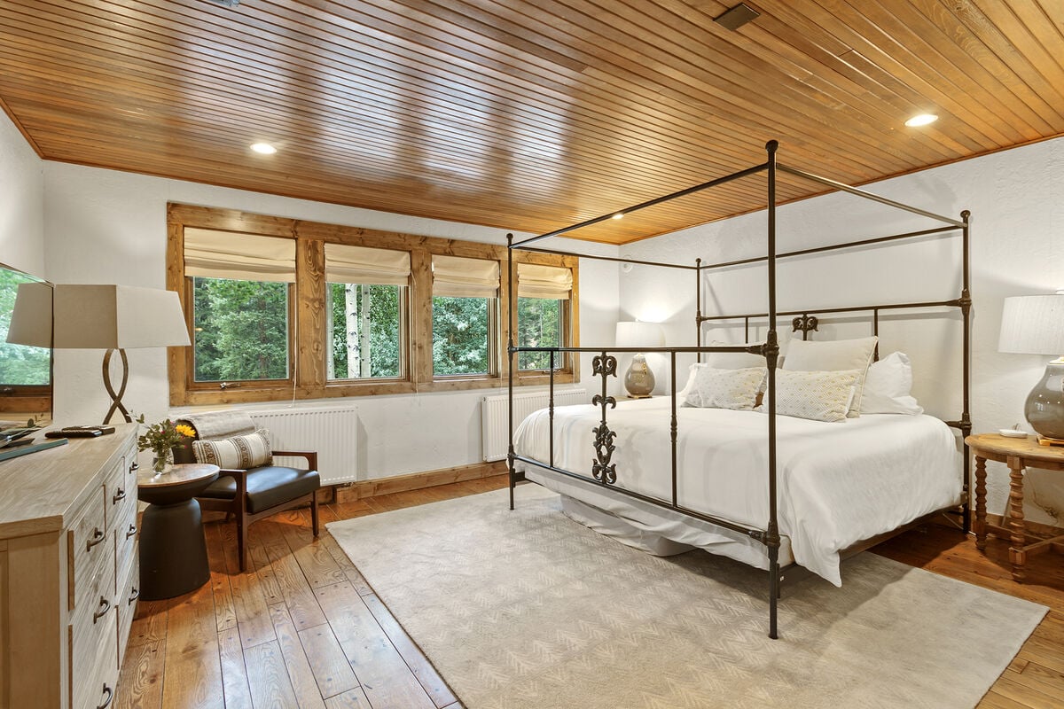The second Master Suite is expansive, featuring beautiful views of the wooded surroundings, a full ensuite bathroom with glass surround shower, Smart TV,  and an extra rollaway bed or additional sleeping options for families.