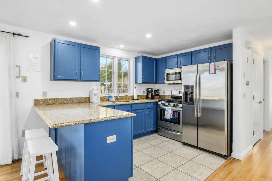 Stainless steel appliances and Admiral Blue cabinetry in this open kitchen - 102 White Rock Road Yarmouth Port Cape Cod - Vacation Station - NEVR