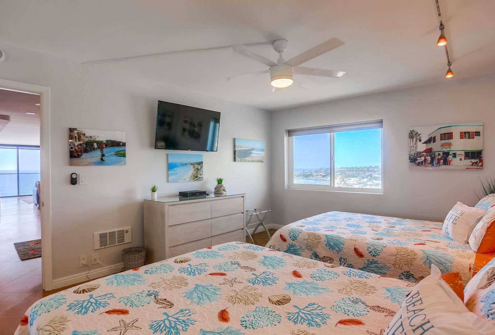 Guest bedroom with 2 queen beds, ceiling fan, closet and dresser storage, full bathroom separate just outside the bedroom, and smart TV with dvr and Cable. Corner beach and ocean views!