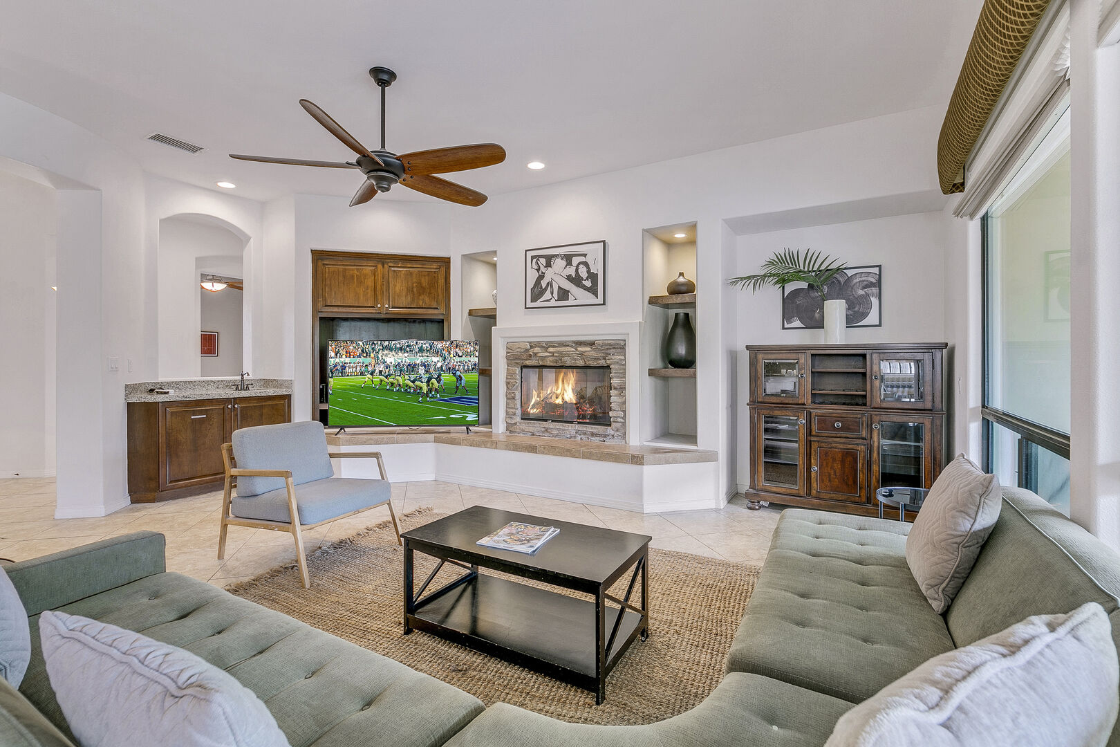 The family room has it all! Remote-controlled ceiling fan, fireplace for chilly nights and sink area.