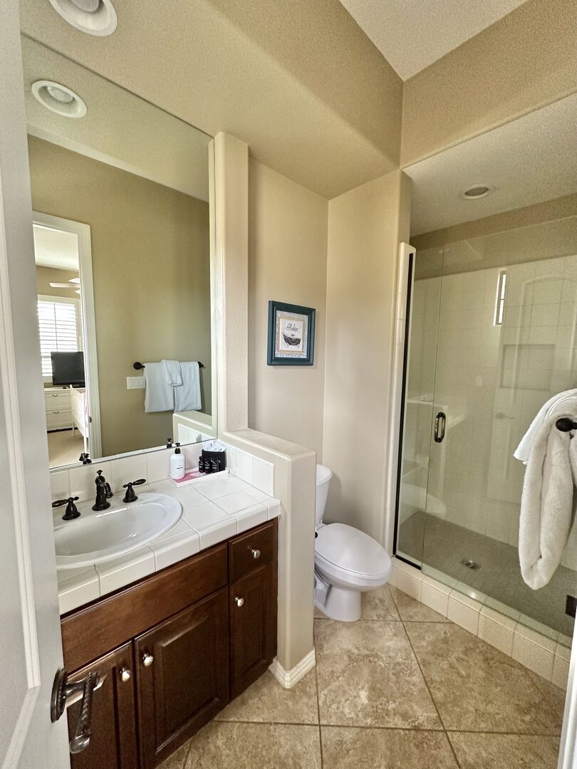 The private, en suite bathroom features a tile shower and a vanity sink.