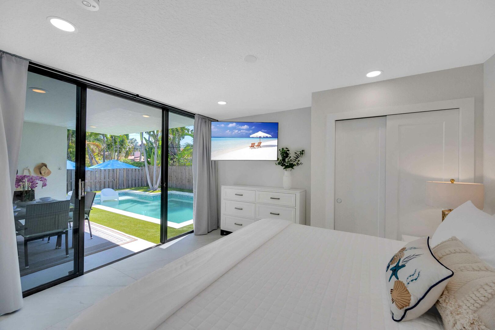 Bedroom two displays a king bed, smart TV and a glass doors to the backyard and pool.