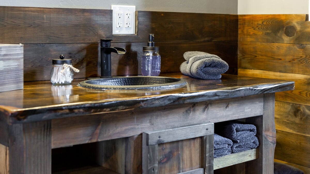 Enjoy our rustic ambiance featuring custom-made, expertly crafted oversized vanities. This uniquely designed furniture offers ample storage space, providing a convenient and stylish solution to store all your travel essentials.  (Room 7)