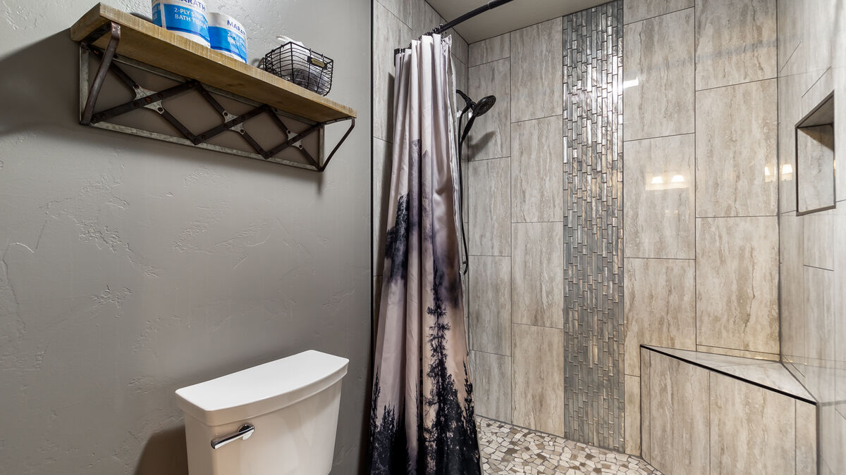 Indulge in a tranquil shower experience in our remodeled step-in tiled shower, featuring a stunning waterfall design, convenient corner bench, and a handy handheld showerhead. Luxurious shower amenities provided so you don't have to pack them.