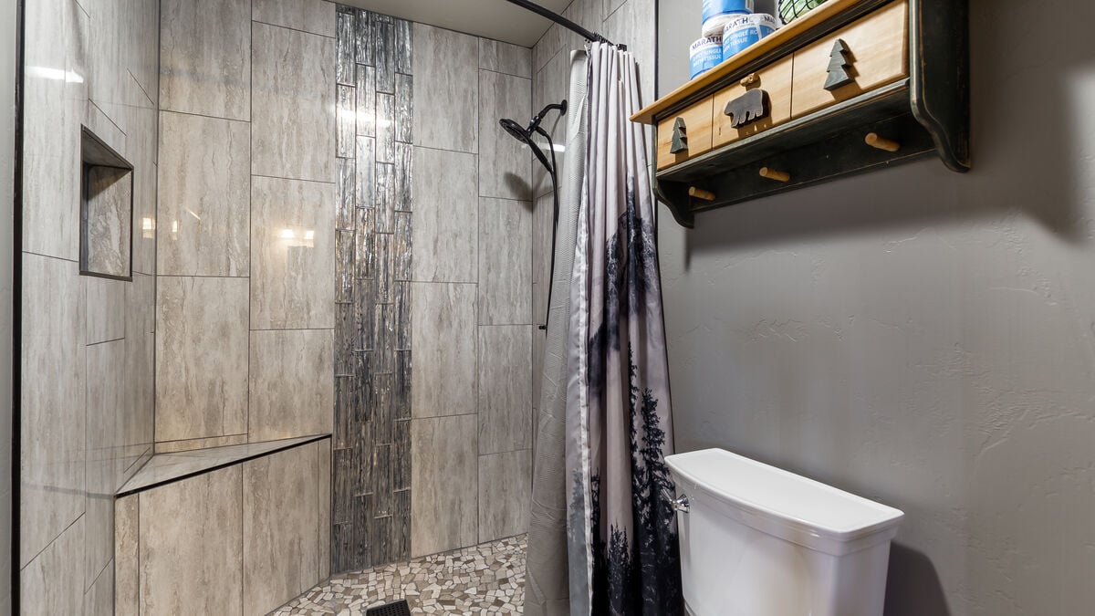 Indulge in a tranquil shower experience in our remodeled step-in tiled shower, featuring a stunning waterfall design, a convenient corner bench, and a handy handheld showerhead. Luxurious shower amenities are provided so you don't have to pack them.