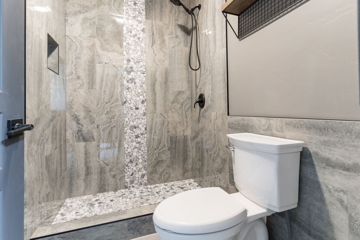 Enjoy a tranquil shower experience in our remodeled step-in tiled shower, with a stunning waterfall design, a convenient corner bench, and a handy handheld showerhead. We provide luxurious shower amenities and a hair dryer. (Room 1)
